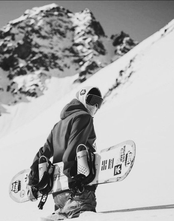 a snowboarder is walking up the side of a mountain with his board in hand