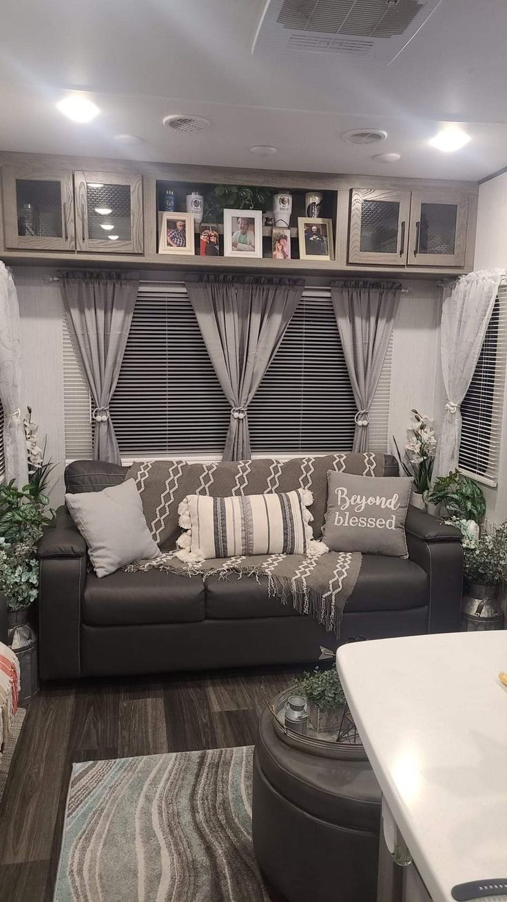 a living room filled with furniture and lots of window coverings on the windowsill