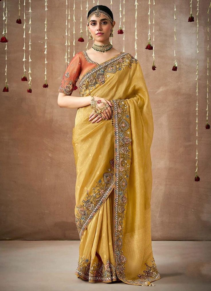 Elevate your bridal look with our Excellent Mustard Beads And Embroidered Organza Silk Saree. The delicate mustard beads and intricate embroidery add a touch of luxury to this saree, perfect for a wedding. Complete the look with the contrasting orange embroidered fancy blouse. Make a statement on your special day with this stunning saree. The unstitched blouse can be customized upto 44 inches. Do Note: All the accessories shown are for styling purpose only. Slight color variation may occur due t Organza Silk Saree, Designer Silk Sarees, Thai Silk, Yellow Saree, Ghagra Choli, Contrast Blouse, Embroidered Wedding, Fancy Blouses, Blouse Work