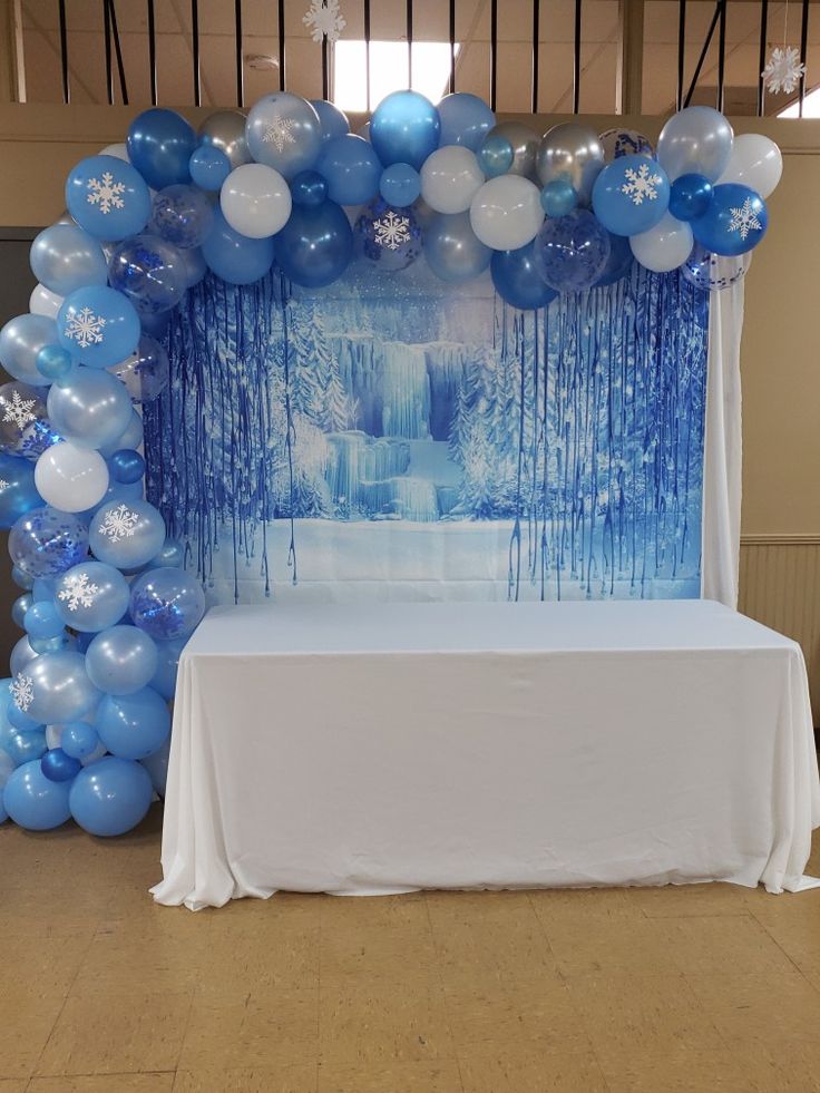 a table topped with blue and white balloons