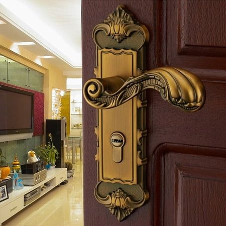 an ornate door handle on a wooden door in a room with a flat screen tv