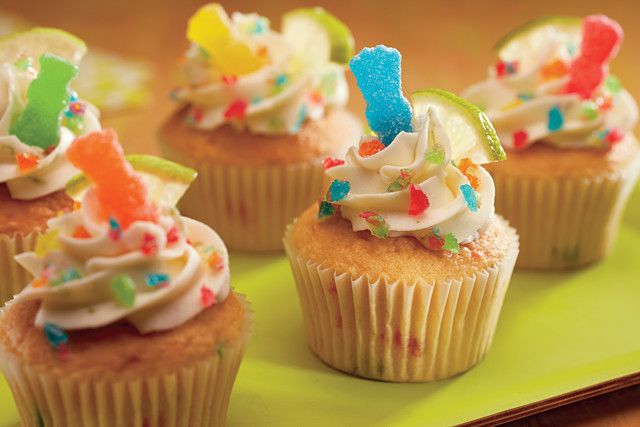 cupcakes with white frosting and colorful sprinkles on a green plate