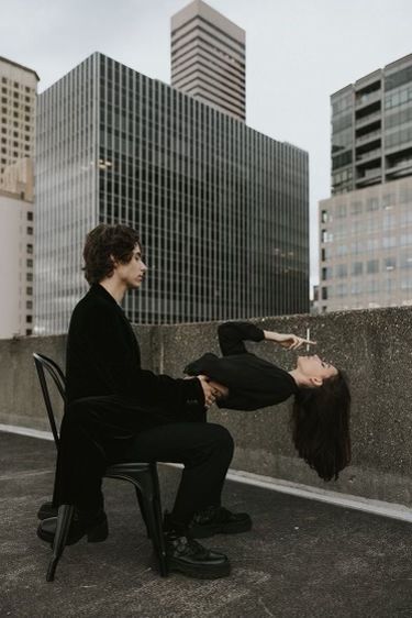 a man and woman sitting on chairs in front of tall buildings