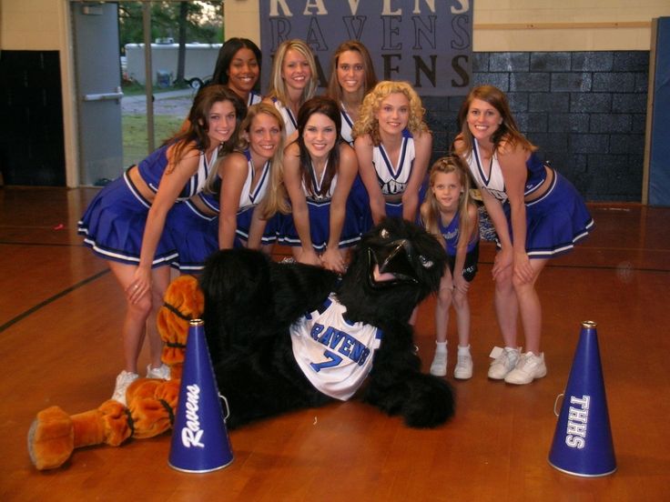 a group of cheerleaders posing for a photo with a dog in front of them