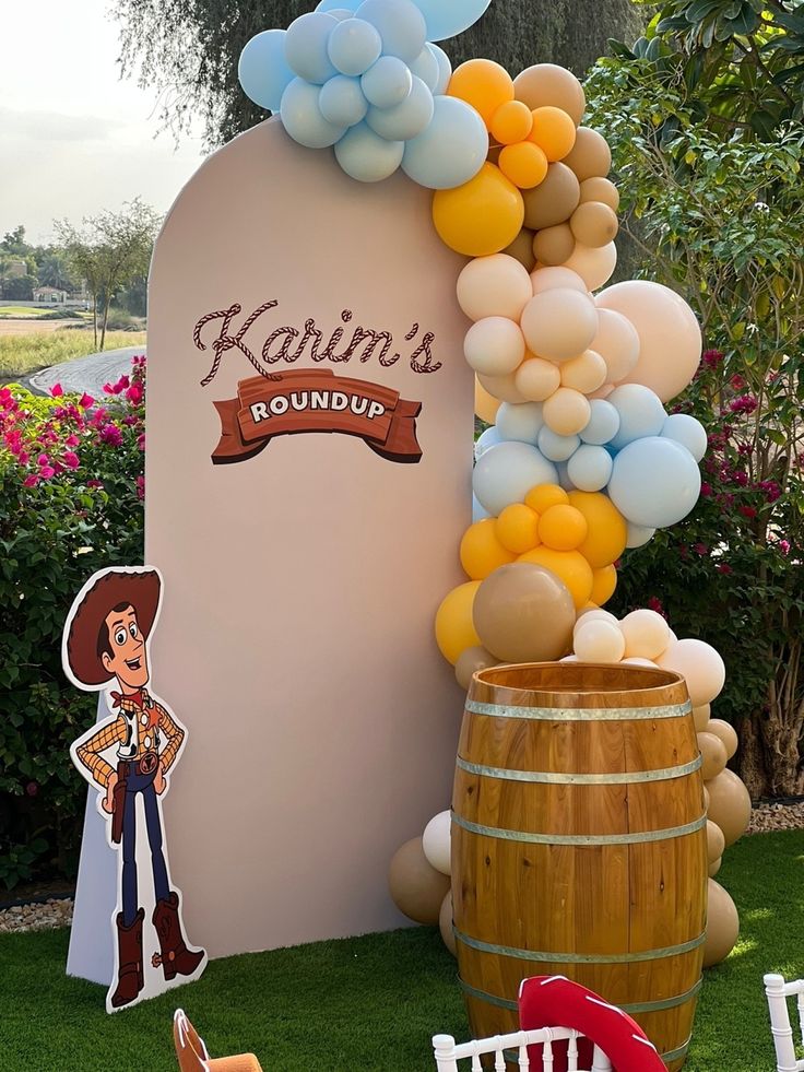 an outdoor party with balloons and decorations on the grass, including a barrel as decoration