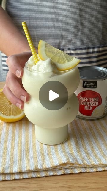 a person is holding a lemonade drink with a straw in it and some ice cream on the table