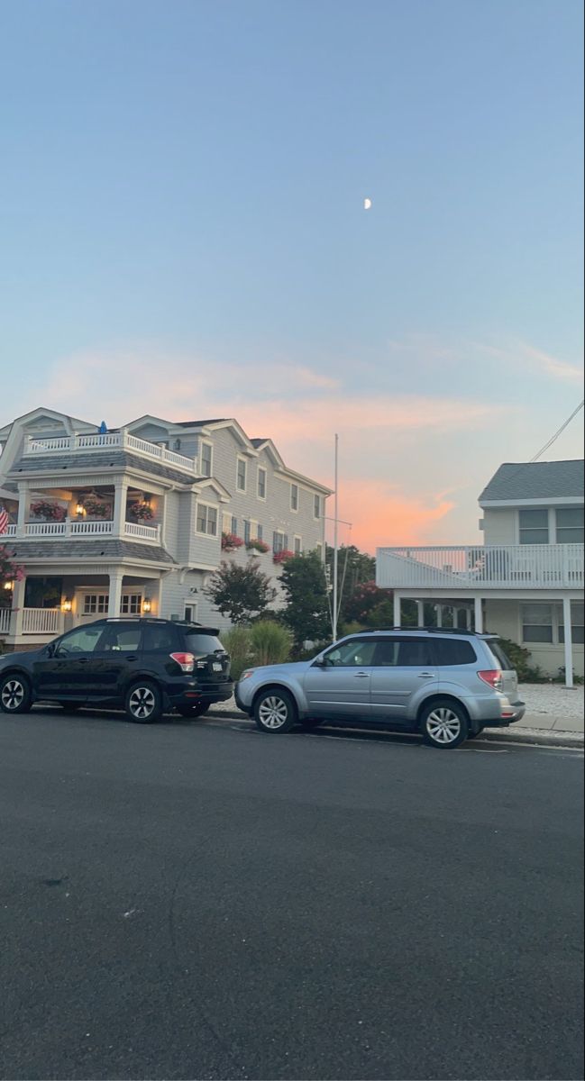 two cars are parked on the street in front of some houses with balconies