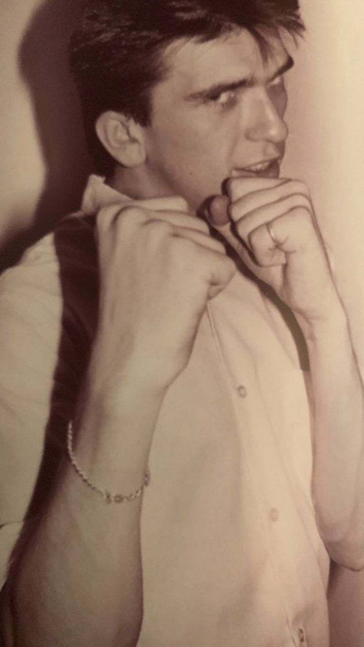 black and white photograph of a man holding his hand to his mouth while wearing a collared shirt