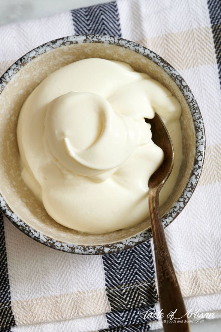 a spoon in a bowl filled with whipped cream on top of a checkered table cloth