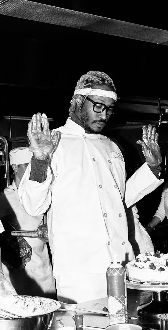 black and white photograph of two men in chef's uniforms, one holding his hands up