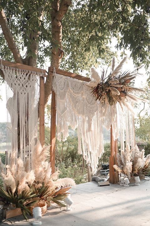 an outdoor wedding ceremony setup with macrame and pamolite hanging from the trees