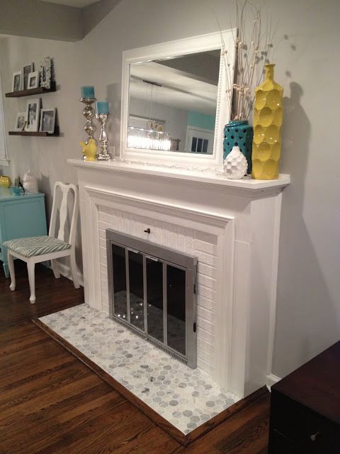 the fireplace is painted white and has been decorated with blue and yellow accessories on it