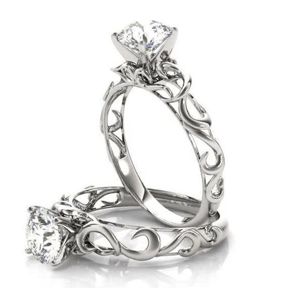 two engagement rings, one with a heart and the other with an intricate design on it