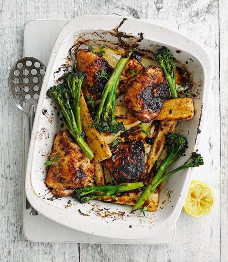 chicken and broccoli in a baking dish with lemon wedges on the side