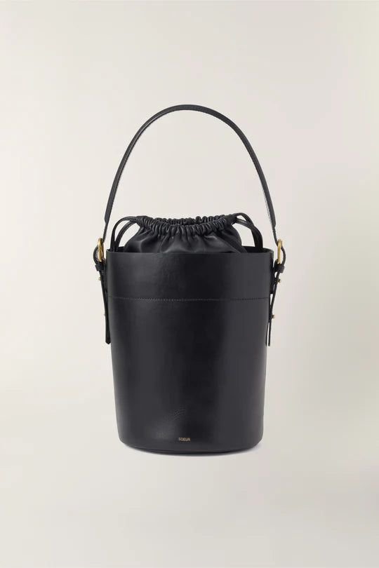 Black leather bucket bag- Hand, shoulder, or cross-body bag- Golden metallics- Fastens with an inner leather drawstring pouch- Height 26 cm, depth 18 cm- One removable leather handle - length 77 cm - One removable cotton handle - length 106 cm Denim Editorial, Black Bucket Bag, Black Bucket, Buffalo Leather, Leather Bucket Bag, Leather Bucket, Drawstring Pouch, Black Bag, Small Leather Goods