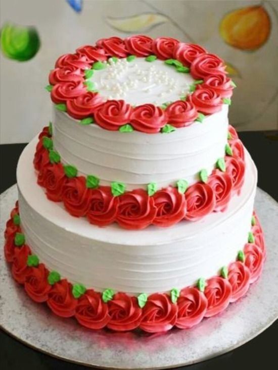 a three tiered cake with red and green decorations on the top, sitting on a silver platter