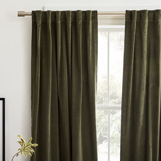 a green curtain hanging in front of a window with a potted plant next to it