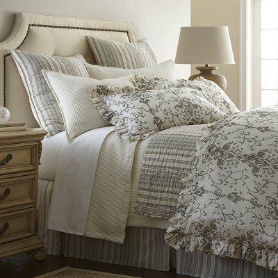 a bed with white and gray comforters in a bedroom