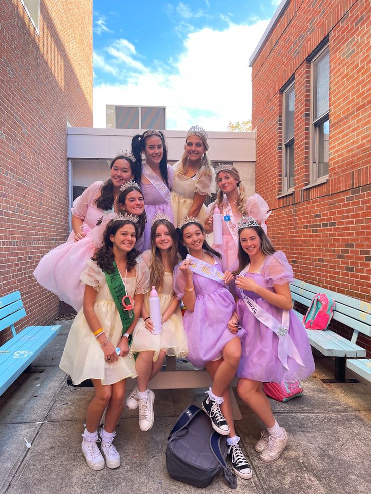 a group of young women dressed in costume posing for a photo on a bench outside