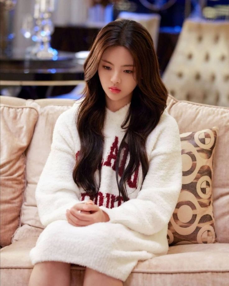 a woman sitting on top of a couch wearing a white sweater