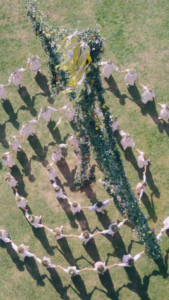 a group of people standing on top of a lush green field next to each other