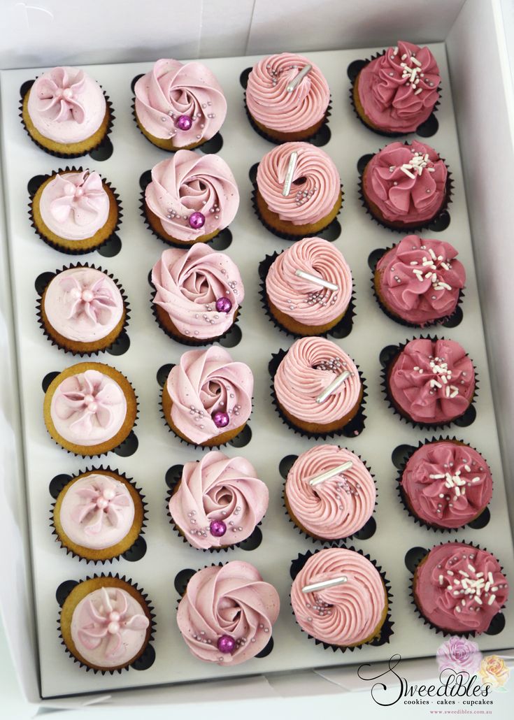 a box filled with lots of pink cupcakes on top of a white table