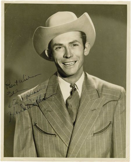 a black and white photo of a man in a suit with a cowboy hat on