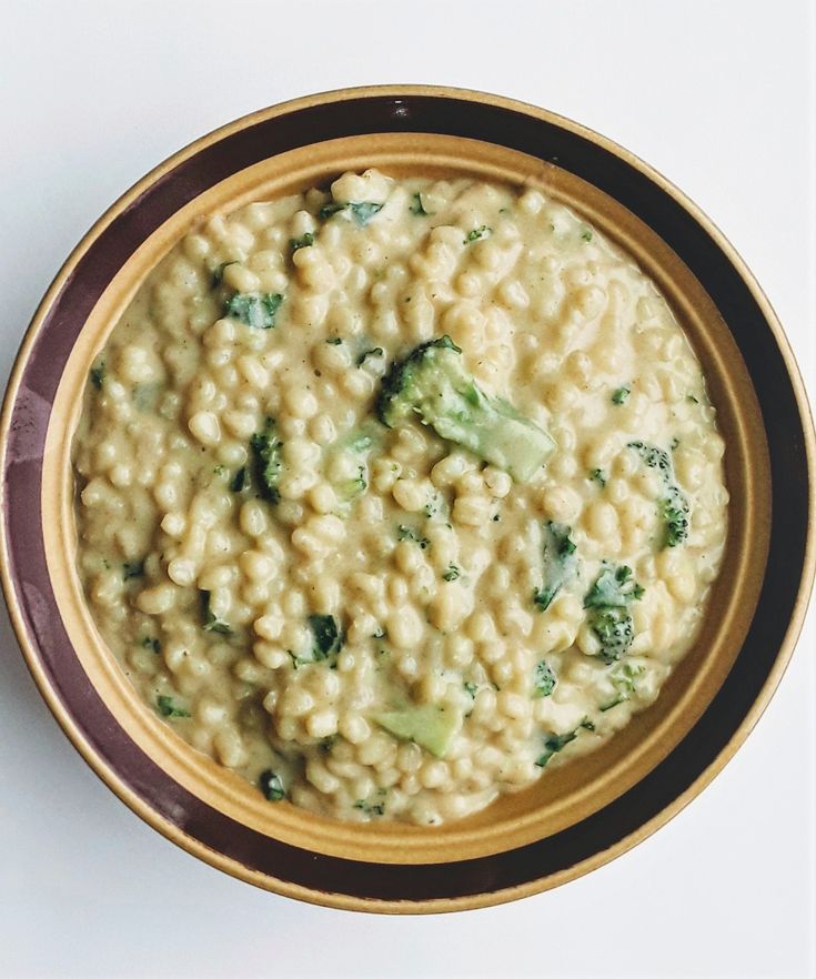 a bowl of macaroni and cheese with broccoli in it on a white surface