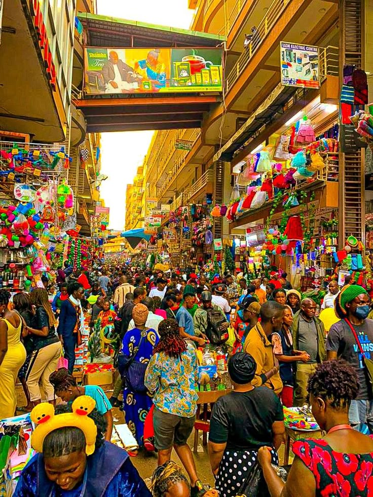 many people are walking through an open market area with lots of colorful items on display