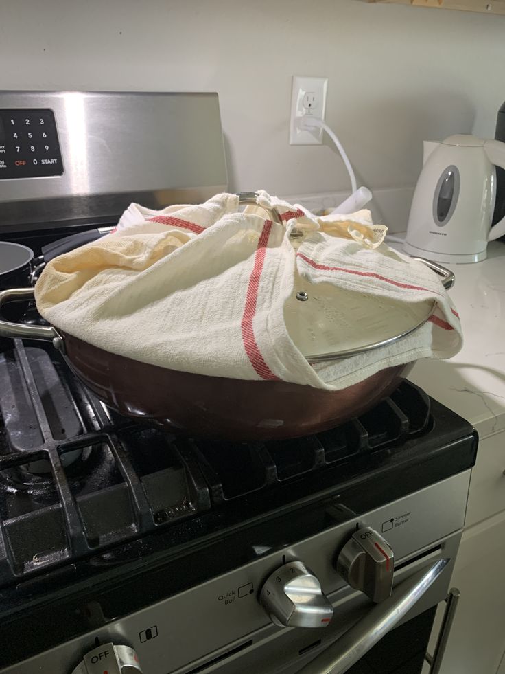 a pan is sitting on top of an oven with a cloth over the burner