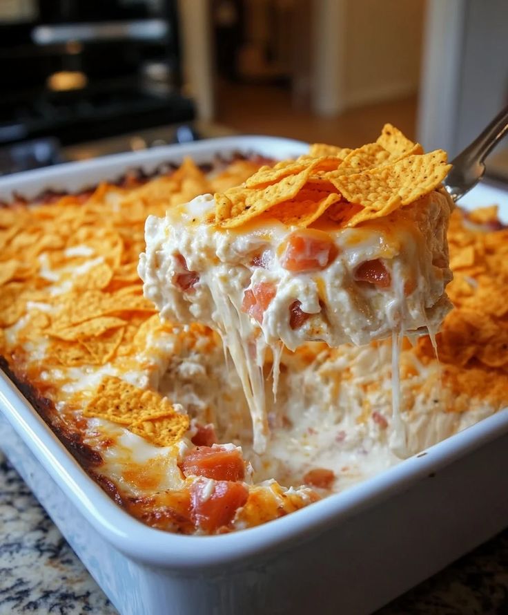 a casserole dish filled with potato chips and dip is being held by a fork