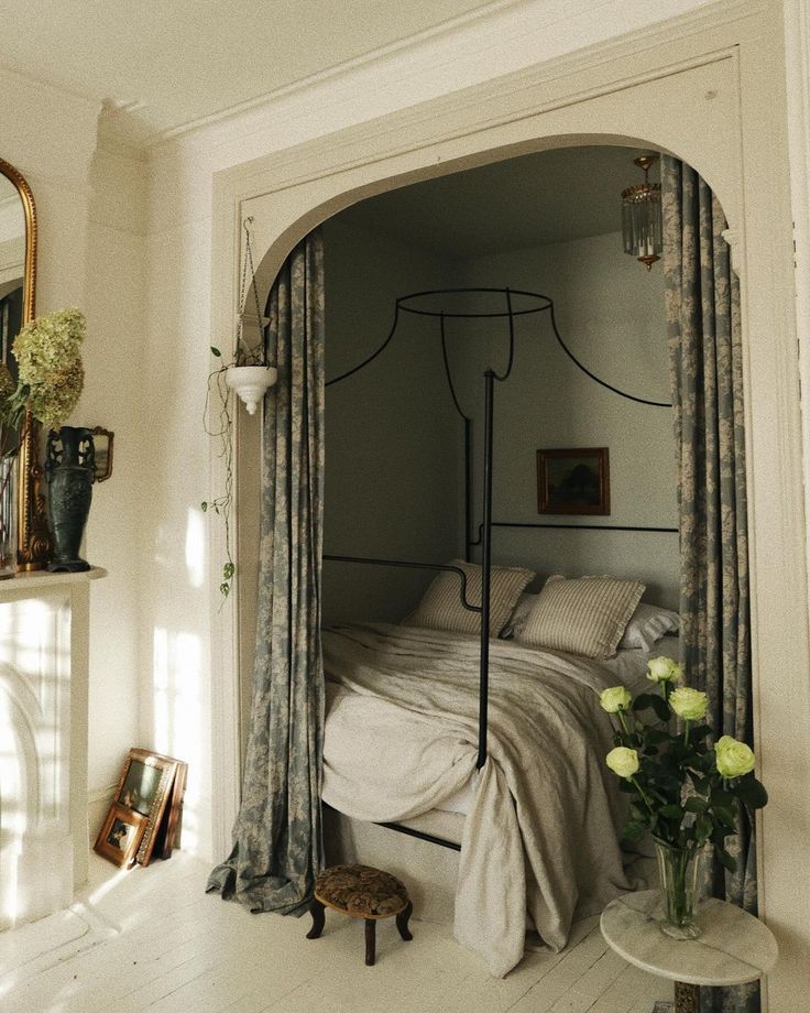 a bedroom with a canopy bed and flowers in vases on the floor next to it