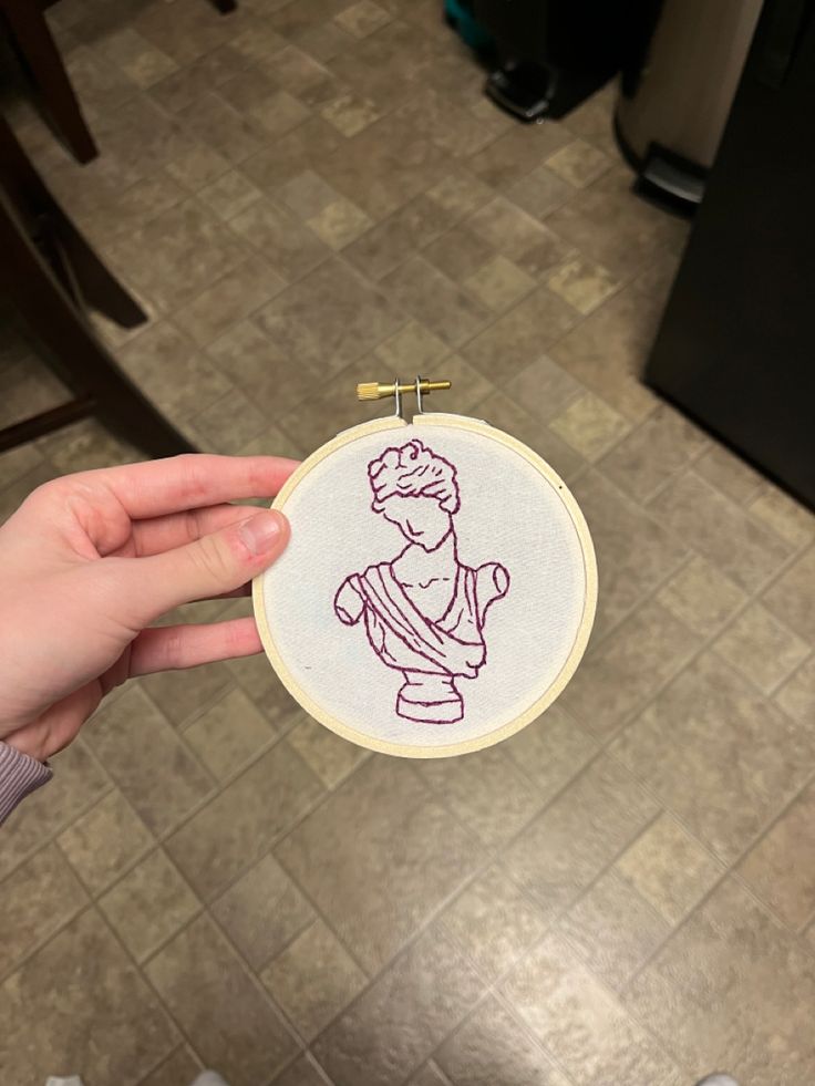 a person holding up a small embroidered item