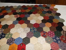 a large quilt is laying on top of a white tablecloth covered with hexagons