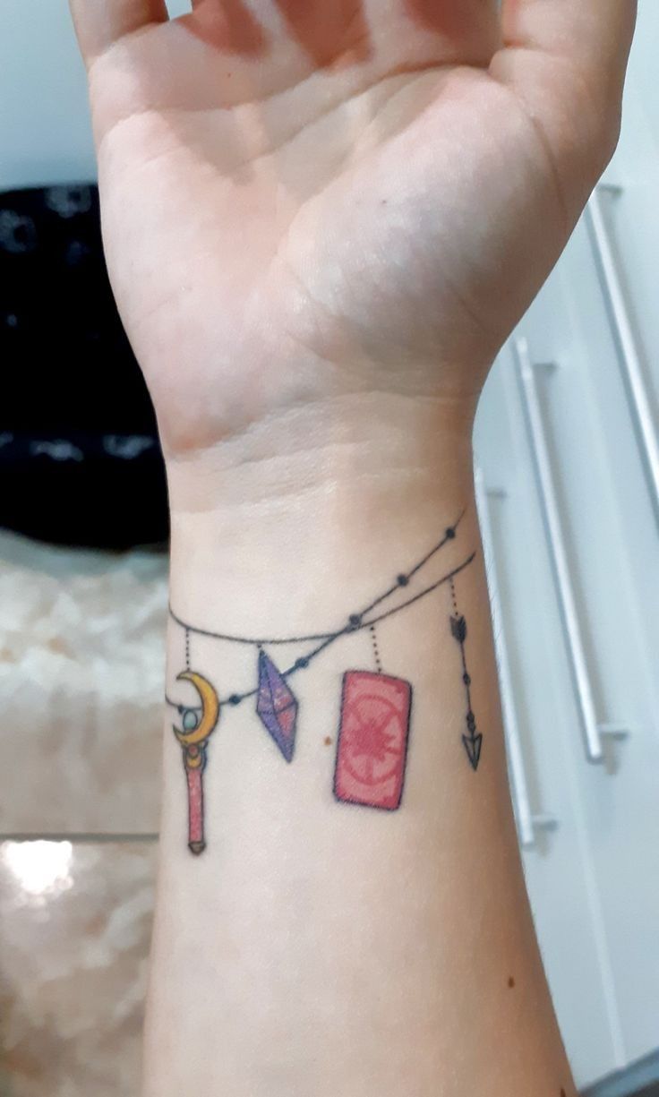 a woman's wrist with a tattoo on it that has some items hanging from the line