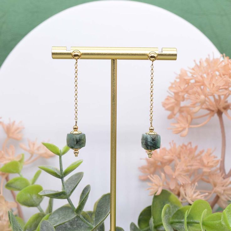 Our Emeralds In Motion earrings are created with one of the world's most precious gemstones, the emerald. Designed with quality in mind and handmade to impress this stunning pair of earrings features faceted, raw emeralds and draped on a shiny pair of 14k gold-filled ball ear posts and sparkly 14k gold-filled rolo chain that beautifully sways and contours the frame of your face with every move. There's something so fun and flirtatious about drape earrings and is a must-have in every jewelry coll Faceted May Birthstone Earrings Gift, Green Moss Agate Earrings For Gift, Single Emerald Earring For May Birthstone, Gift Emerald Crystal Dangle Earrings, Emerald Drop Earrings For May Birthstone, Natural Stones Dangle Earrings For May Birthstone, Dangle Earrings With May Birthstone Gemstone, May Birthstone Gemstone Dangle Earrings, May Birthstone Dangle Earrings With Gemstone