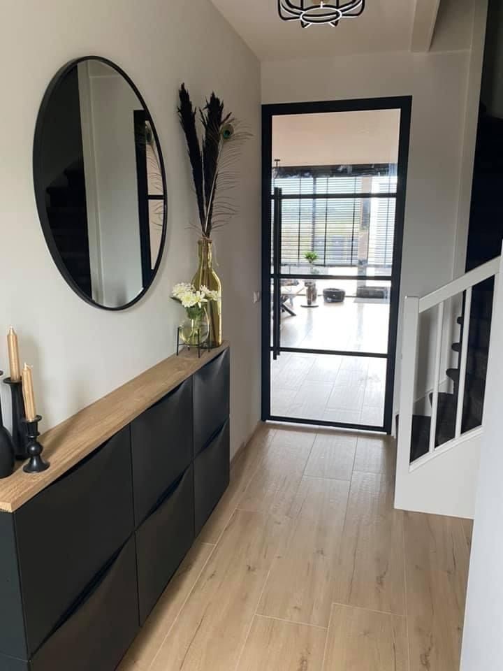 a hallway with a black cabinet and round mirrors on the wall, along with a wooden floor