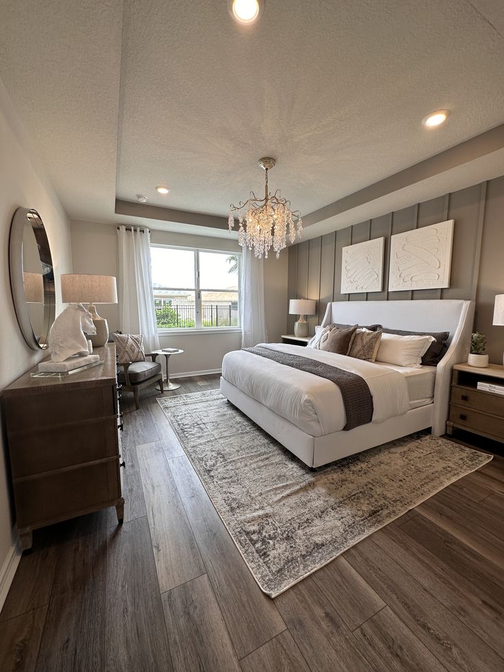 a large bed sitting in a bedroom on top of a wooden floor next to a window