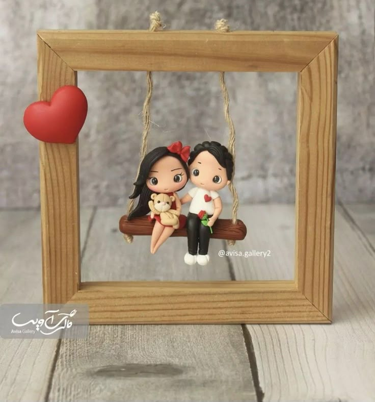 a couple sitting on a swing with a heart hanging from the frame in front of them