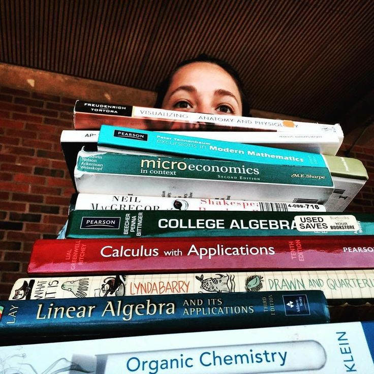 a stack of books stacked on top of each other in front of a brick wall