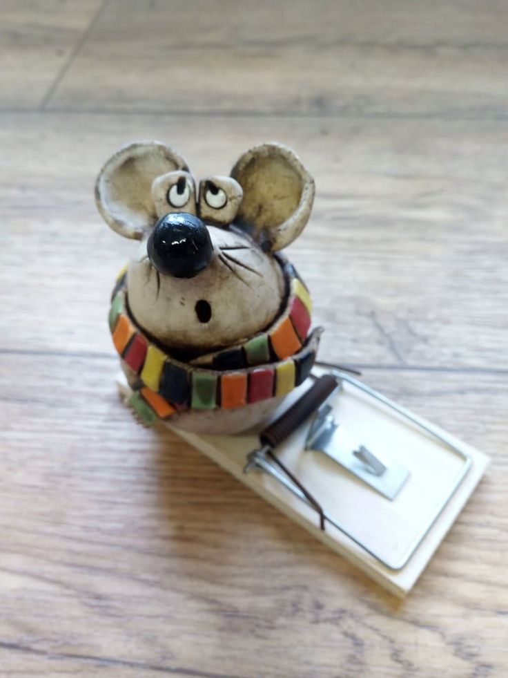 a mouse figurine sitting on top of a wooden floor next to a clipboard