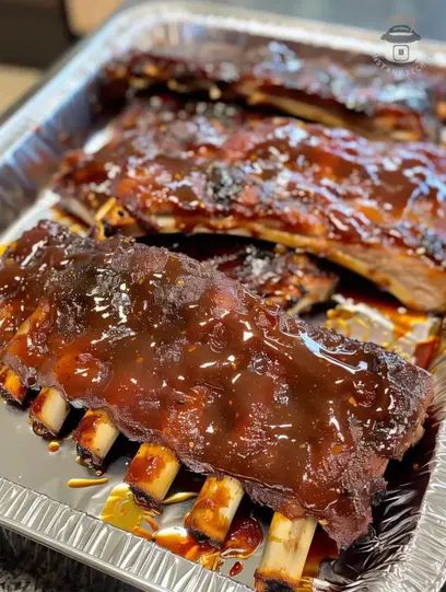 ribs covered in bbq sauce sitting on top of a pan