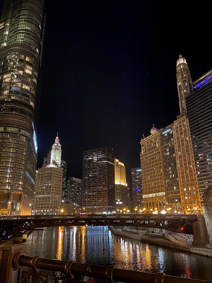 the city is lit up at night with lights reflecting in the water and skyscrapers