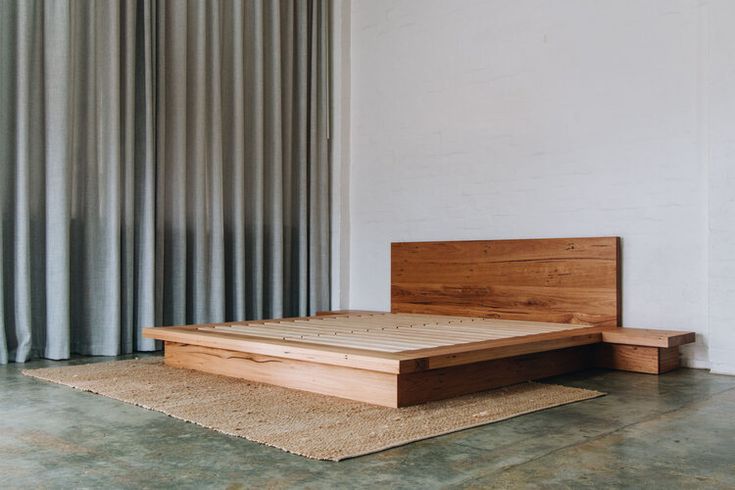 a bed sitting on top of a wooden platform next to a window covered in curtains