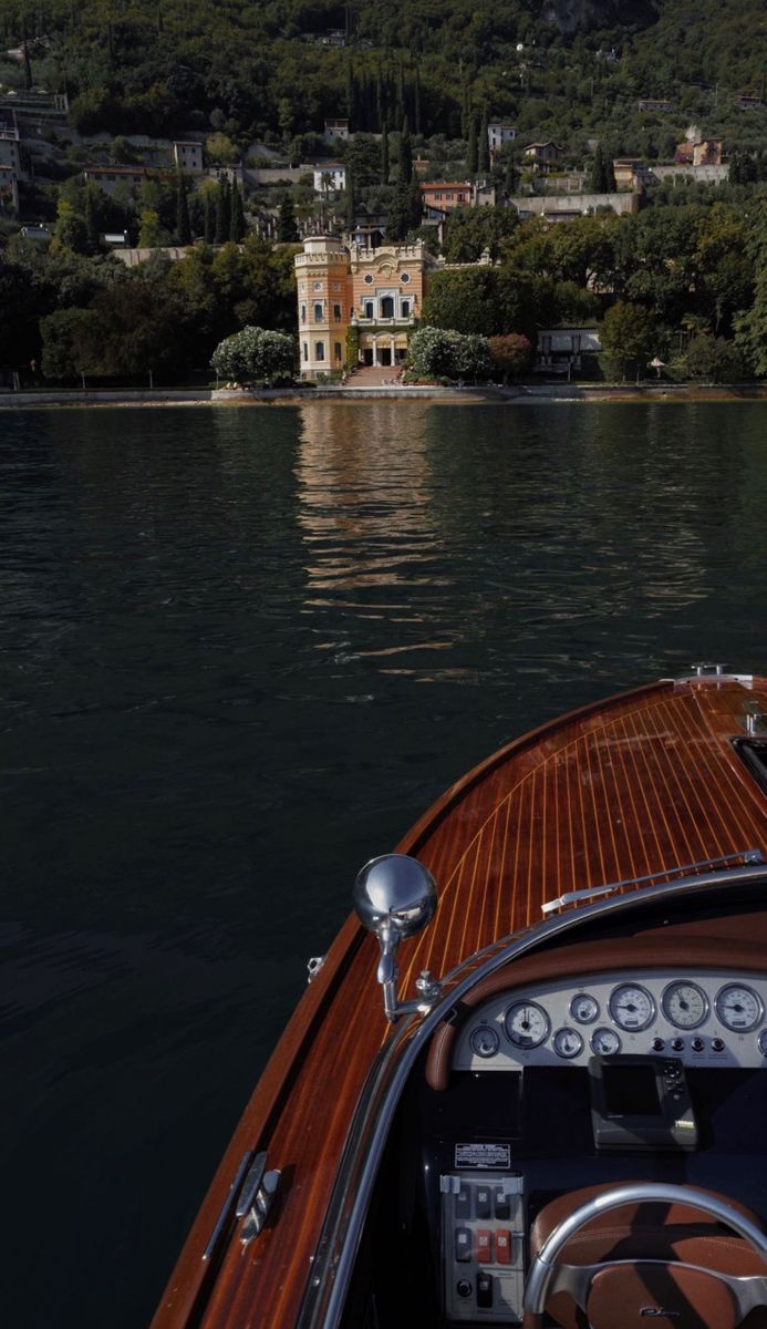 the steering wheel and dashboard of a small boat in front of a lake with houses on it