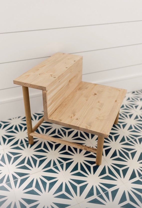 a small wooden table sitting on top of a blue and white tile floor next to a wall