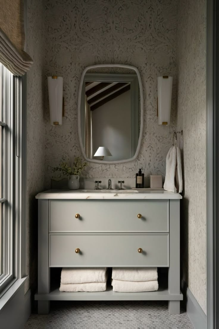 a bathroom with a sink, mirror and two white towels on the counter in front of it