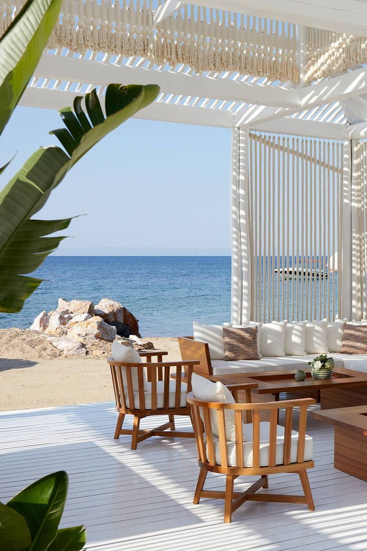 an outdoor seating area with wooden furniture on the beach