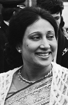 an old photo of a woman smiling in front of other people and one is wearing a necklace