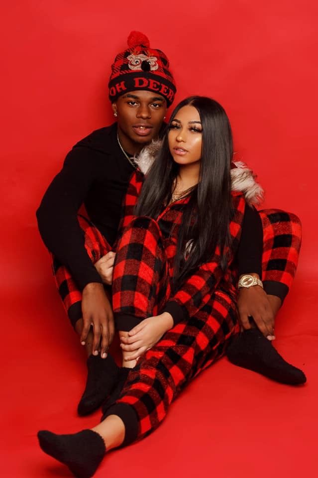 a man and woman sitting next to each other on a red background wearing plaid outfits